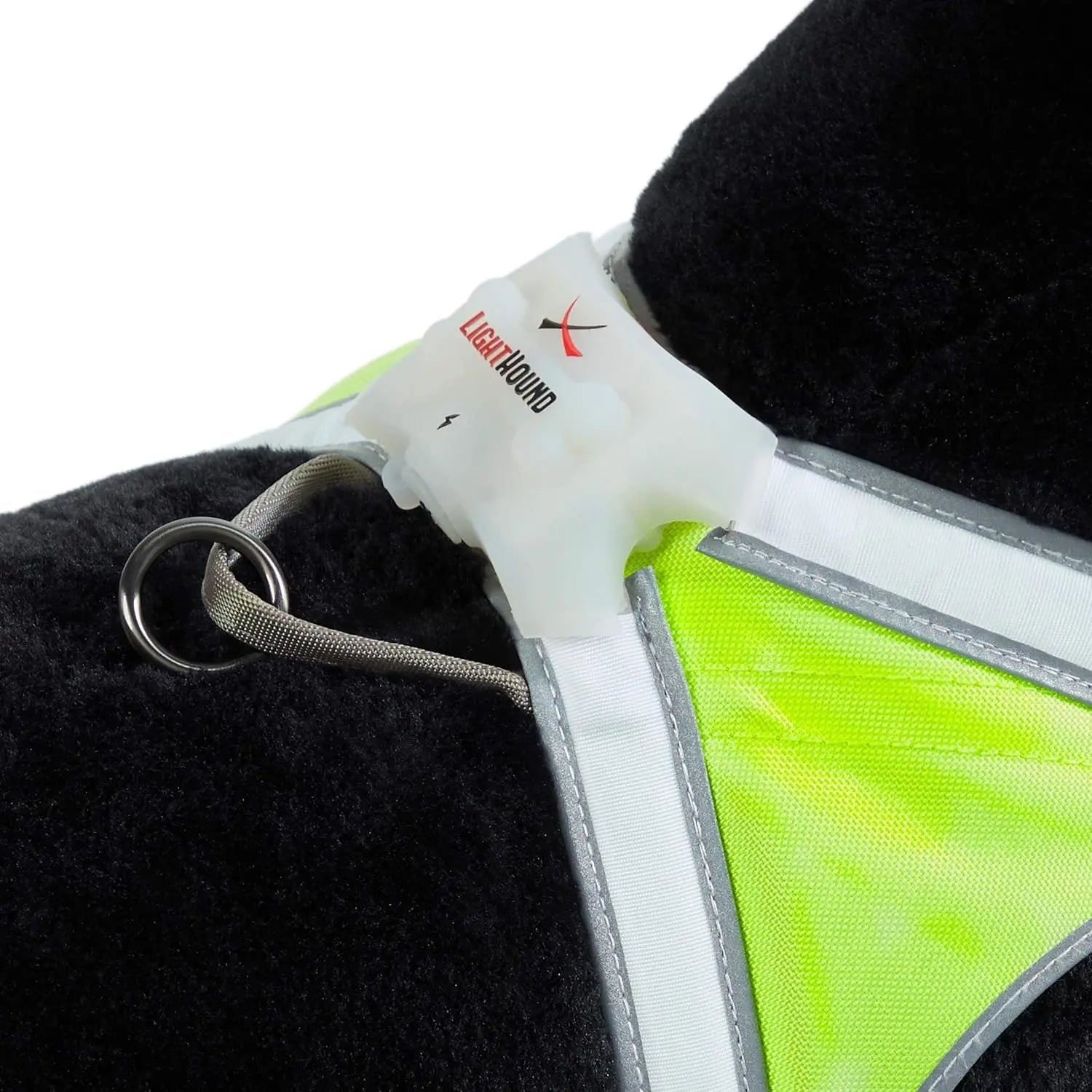 Close-up of a reflective dog vest with a light source attached, on a black background.