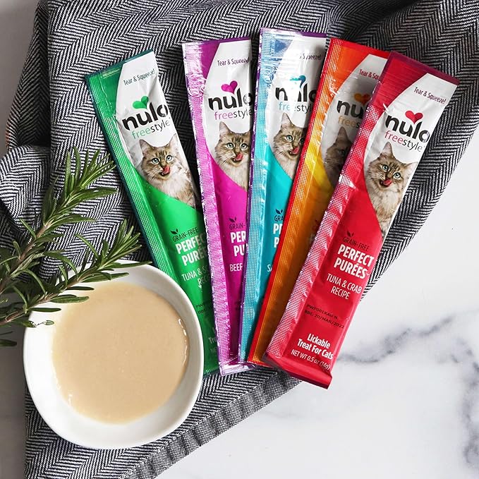 Nulo Freestyle cat food pouches on a marble surface with a bowl of cat food.